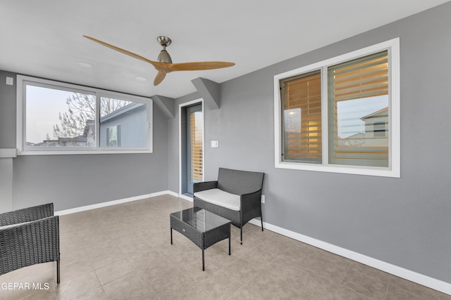 living area with baseboards and a ceiling fan