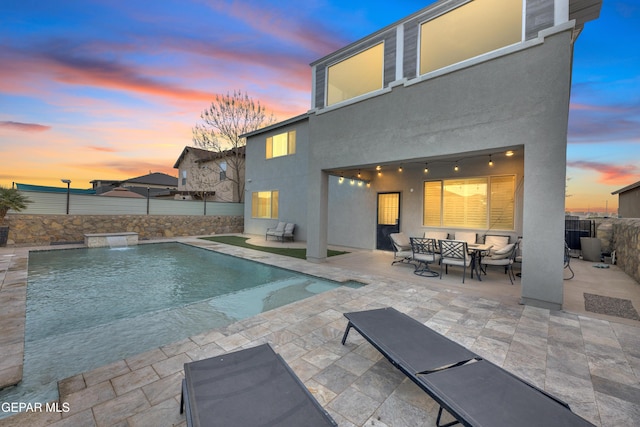 pool at dusk with a patio, fence, and a fenced in pool