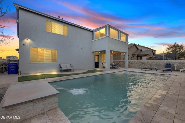 pool at dusk featuring a fenced in pool, fence, and a patio area