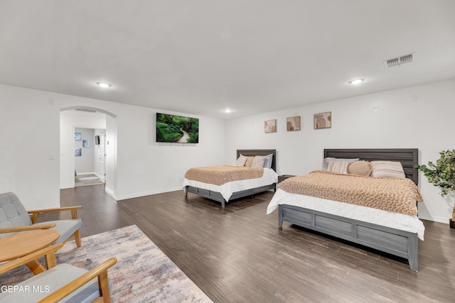 bedroom with wood finished floors, visible vents, baseboards, recessed lighting, and arched walkways