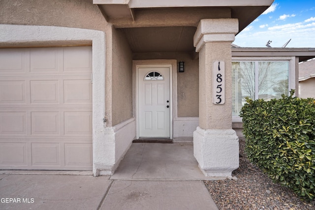 property entrance with a garage and stucco siding