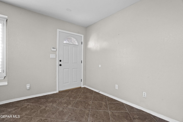 entrance foyer with a wealth of natural light, baseboards, and dark tile patterned floors