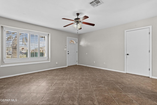 interior space featuring visible vents, baseboards, dark tile patterned flooring, and ceiling fan