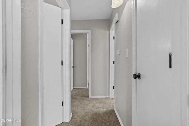 hallway featuring carpet flooring and baseboards