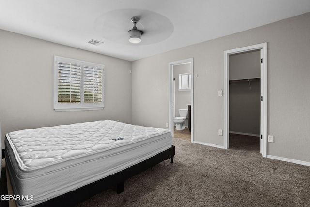 bedroom with baseboards, visible vents, carpet floors, a spacious closet, and connected bathroom