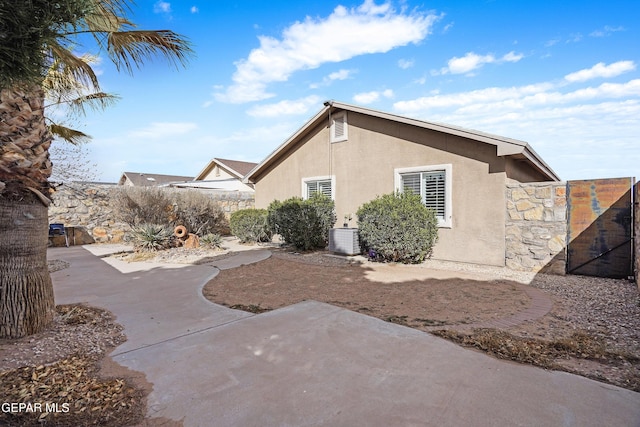 view of property exterior with cooling unit, a patio area, fence, and stucco siding