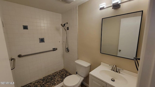 bathroom with tiled shower, toilet, and vanity