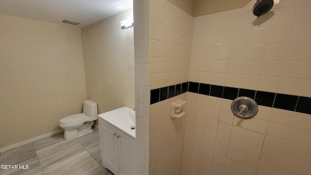 bathroom featuring vanity, toilet, visible vents, and tiled shower