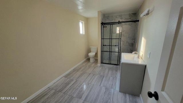 bathroom with a stall shower, toilet, vanity, and baseboards