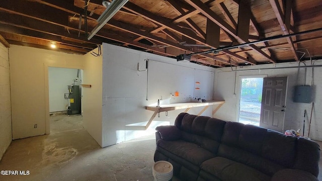 living area featuring water heater, unfinished concrete floors, electric panel, and a garage