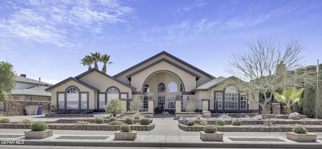 rear view of house with a fenced front yard, stucco siding, french doors, and a gate