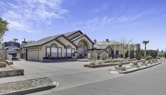 tudor home featuring a garage, a chimney, driveway, and stucco siding