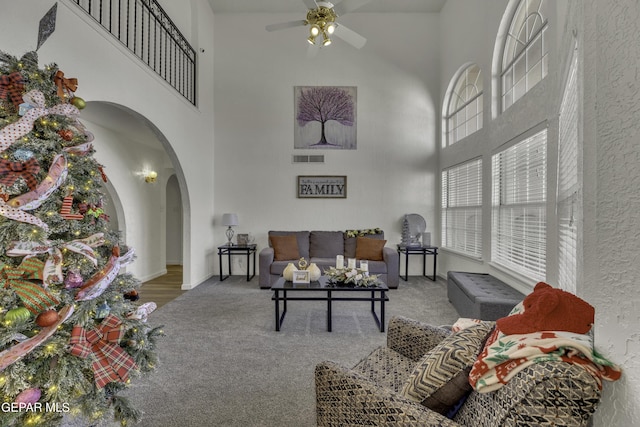 living room with visible vents, arched walkways, ceiling fan, and carpet flooring