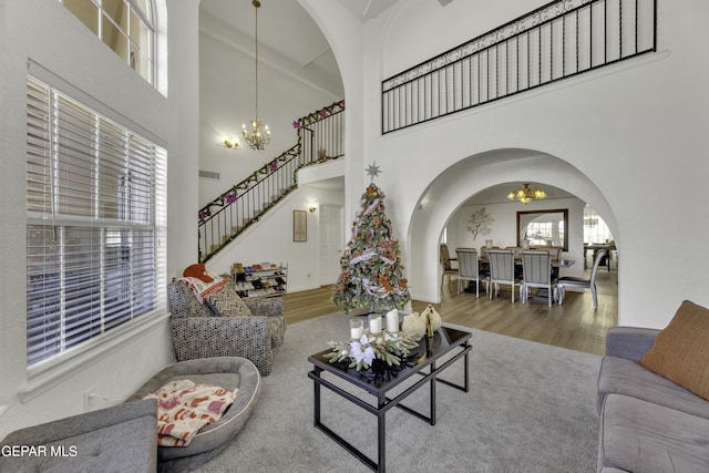 living room featuring stairway, wood finished floors, arched walkways, and a chandelier