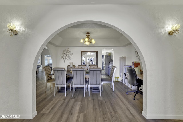 dining area with baseboards, arched walkways, and wood finished floors