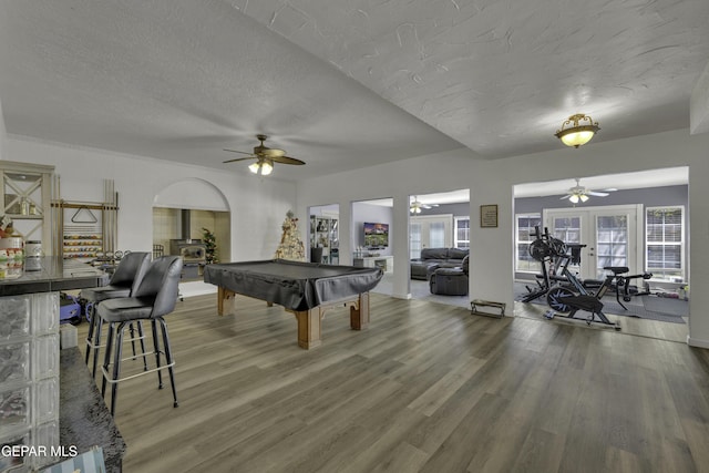 playroom with a wealth of natural light, a textured ceiling, wood finished floors, pool table, and ceiling fan