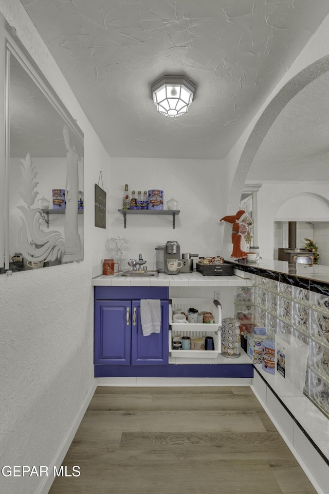 bar featuring wood finished floors, arched walkways, and baseboards