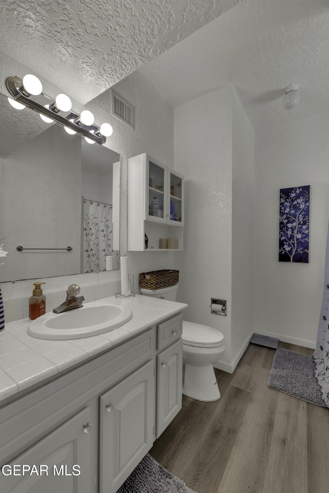 bathroom featuring vanity, wood finished floors, visible vents, and a textured ceiling