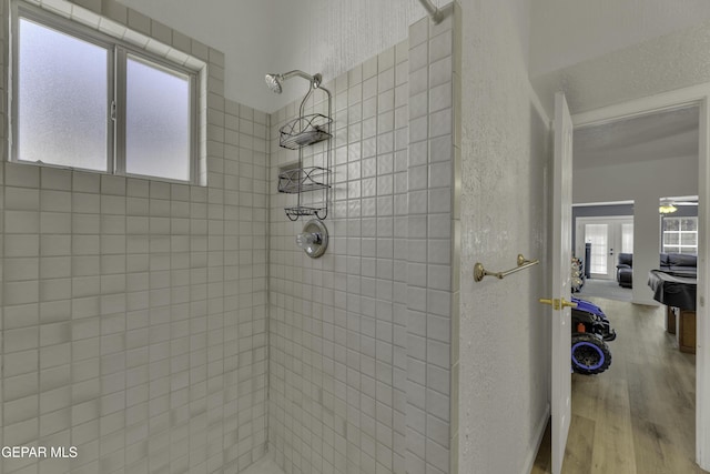 bathroom featuring a tile shower, a textured wall, and wood finished floors