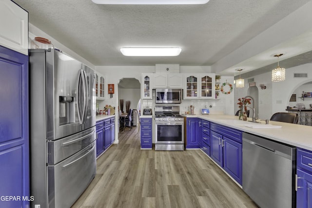 kitchen with visible vents, a sink, stainless steel appliances, arched walkways, and light wood-style floors