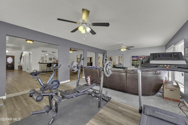 workout room featuring a ceiling fan, light wood-type flooring, and baseboards