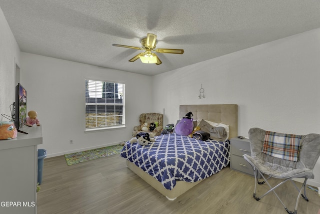 bedroom featuring ceiling fan, wood finished floors, baseboards, and a textured ceiling