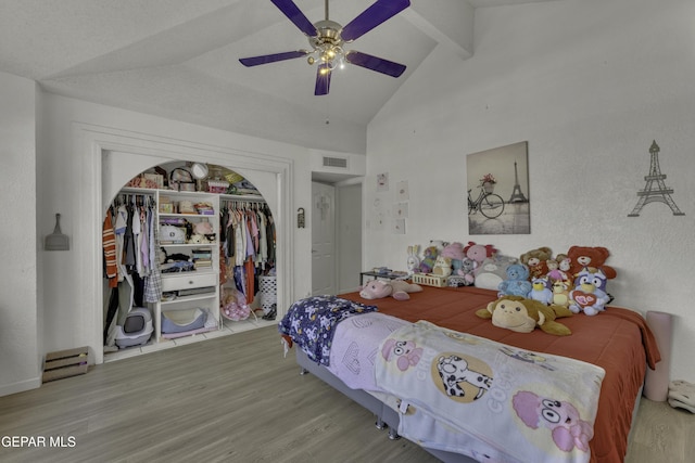 bedroom with a ceiling fan, wood finished floors, visible vents, vaulted ceiling with beams, and a closet