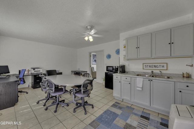 kitchen with ceiling fan, light countertops, light tile patterned flooring, a textured ceiling, and a sink