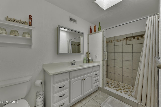 bathroom featuring visible vents, tiled shower, toilet, and vanity