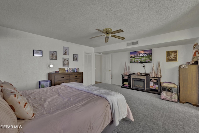 bedroom with visible vents, carpet, ceiling fan, and a textured ceiling