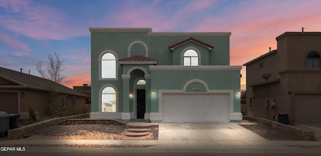 view of front of house with stucco siding, a garage, and driveway