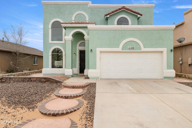 mediterranean / spanish house with a tile roof, an attached garage, driveway, and stucco siding