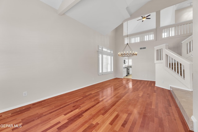 unfurnished living room featuring stairway, wood finished floors, visible vents, baseboards, and ceiling fan with notable chandelier