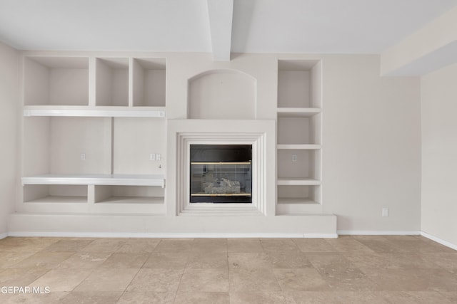 unfurnished living room with a glass covered fireplace, beam ceiling, built in shelves, and baseboards