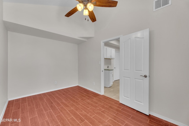 spare room featuring wood finish floors, visible vents, baseboards, and a ceiling fan