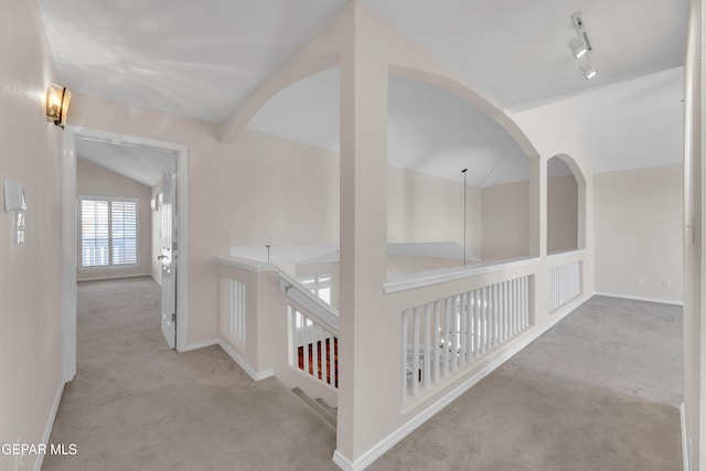 hall featuring track lighting, baseboards, lofted ceiling, and carpet floors