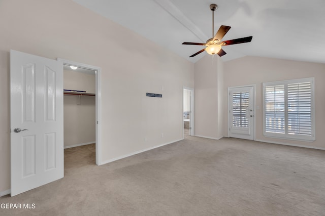 unfurnished bedroom featuring a walk in closet, a ceiling fan, baseboards, and carpet floors