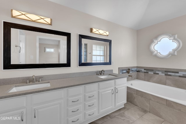 full bathroom featuring a sink, lofted ceiling, a bath, and double vanity