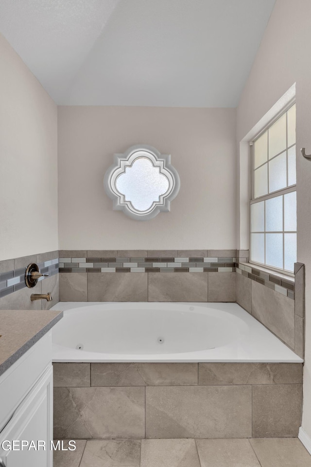 full bathroom featuring a tub with jets and vanity