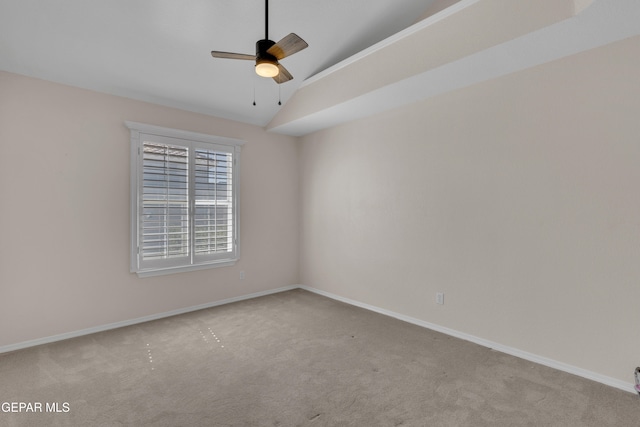 carpeted spare room with vaulted ceiling, a ceiling fan, and baseboards