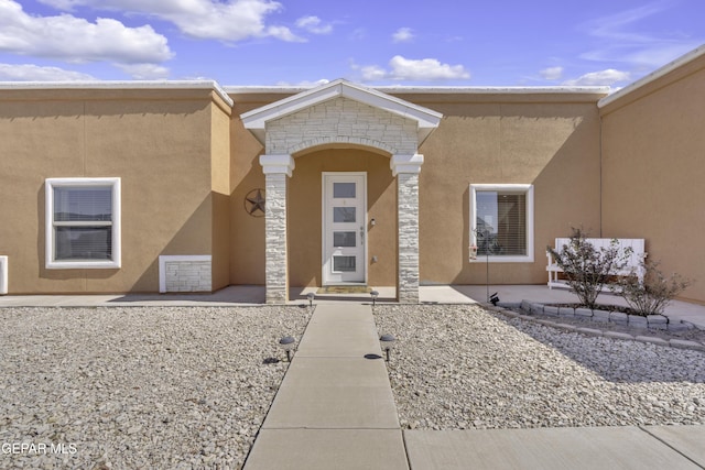 doorway to property featuring stone siding and stucco siding