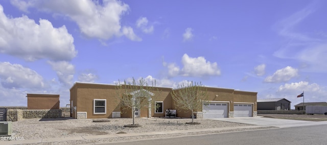 pueblo-style house with concrete driveway, a garage, and stucco siding