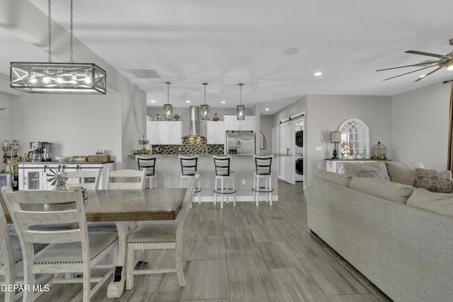 dining room with visible vents, recessed lighting, ceiling fan, stacked washer and dryer, and a barn door