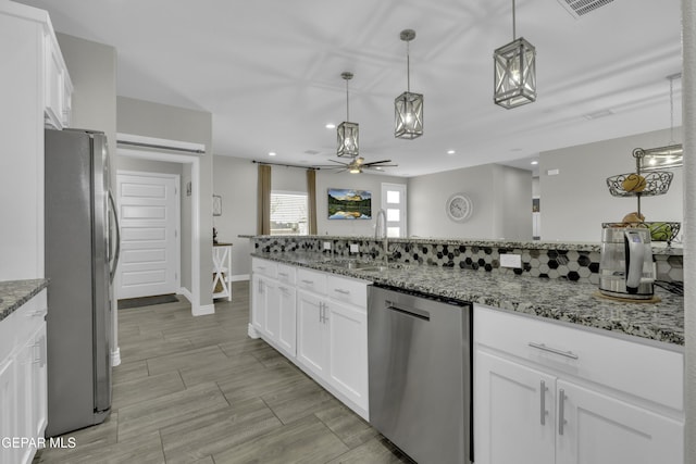 kitchen featuring a sink, stainless steel appliances, stone counters, and white cabinetry