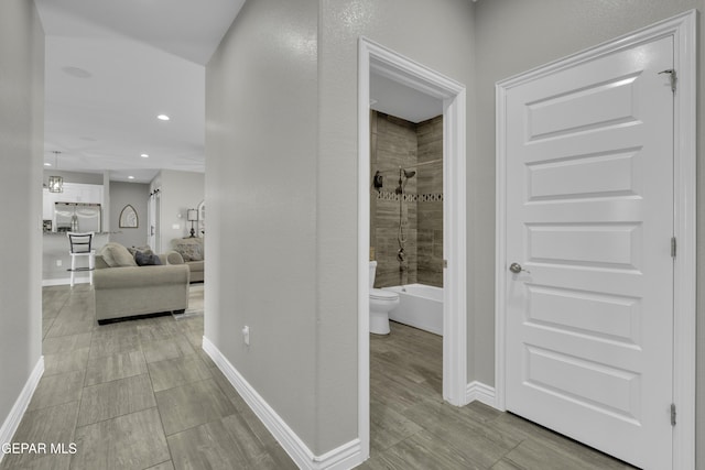 hallway with recessed lighting and baseboards