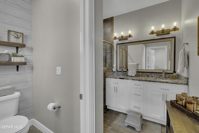 full bath featuring baseboards, toilet, tiled shower, wood finished floors, and vanity