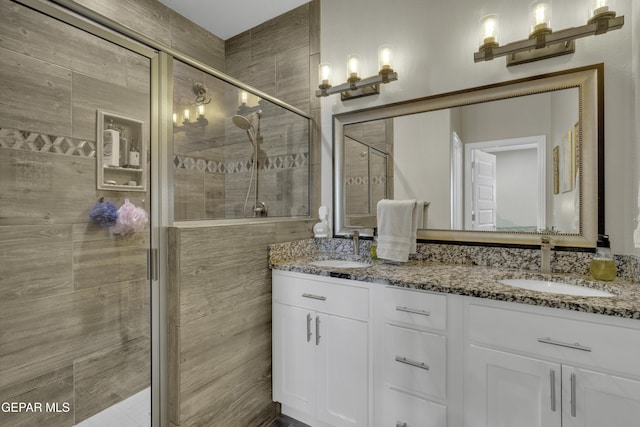 full bath with a sink, double vanity, and a shower stall