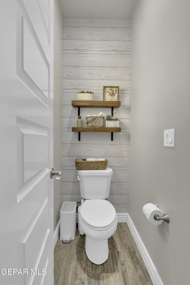 bathroom with baseboards, toilet, and wood finished floors