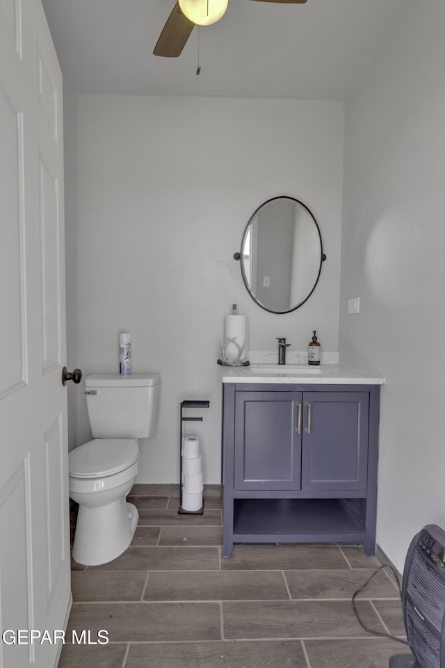 bathroom with ceiling fan, toilet, vanity, and wood finish floors