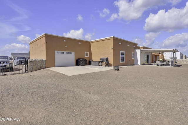 view of property exterior with a patio area, fence, driveway, and stucco siding